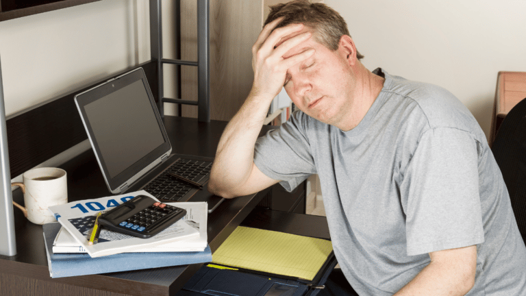 Man sitting as his computer looking very frustrated