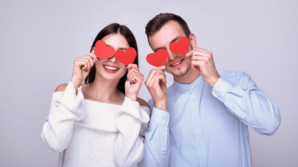 Man and Woman holding paper hearts over their eyes