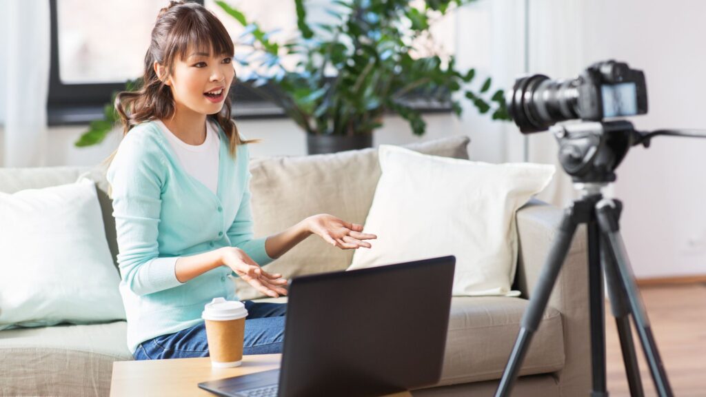 Woman sitting on a couch filming herself with a camera