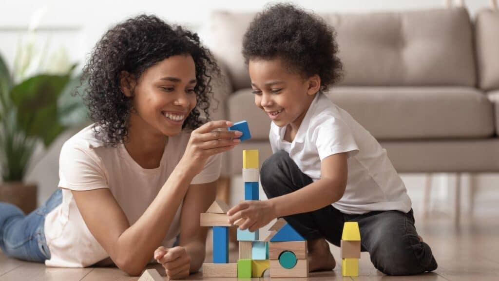 Young woman playing blocks with young boy