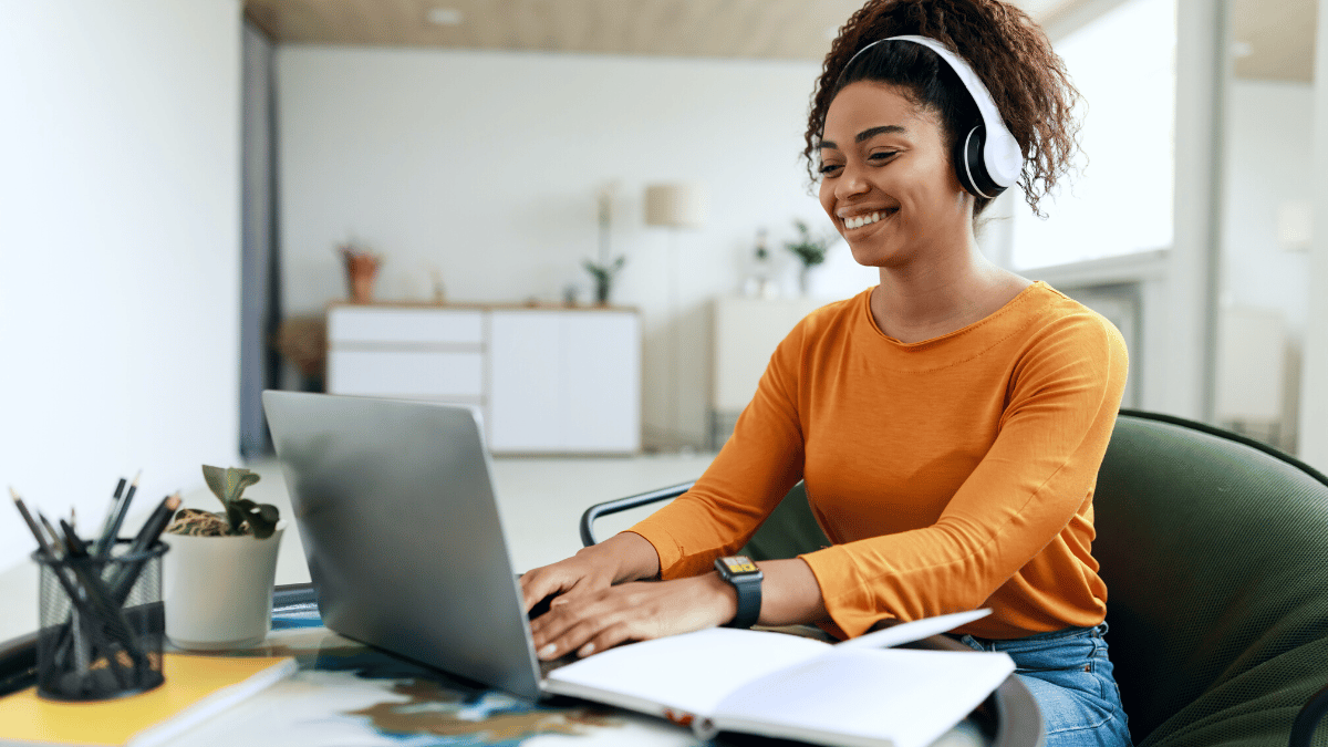 Woman typing on laptop wearing headphones