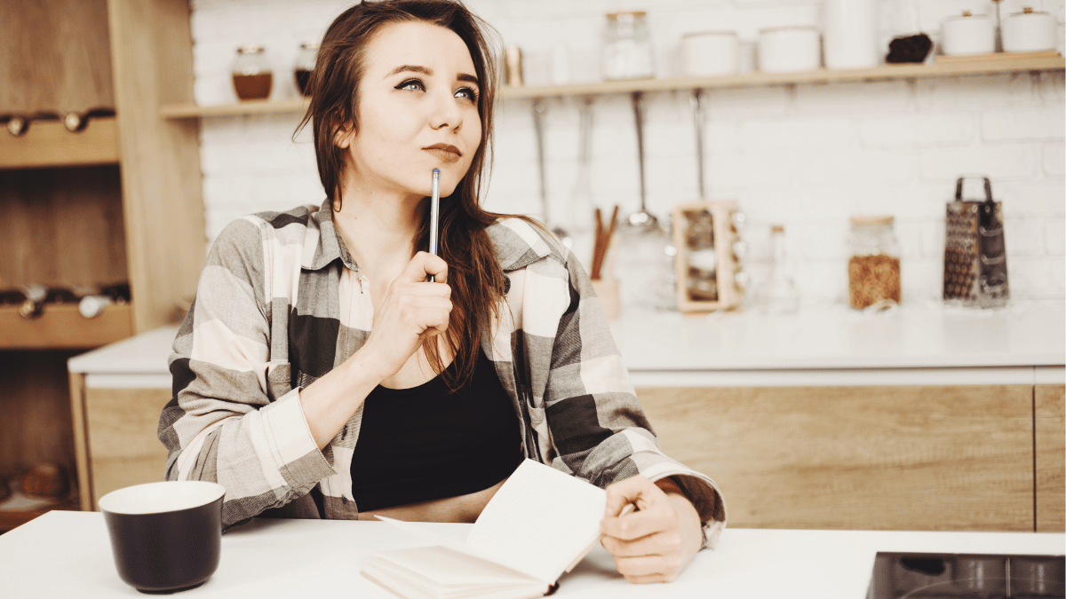 Woman planning out how to organize her kitchen with coffee and a notebook