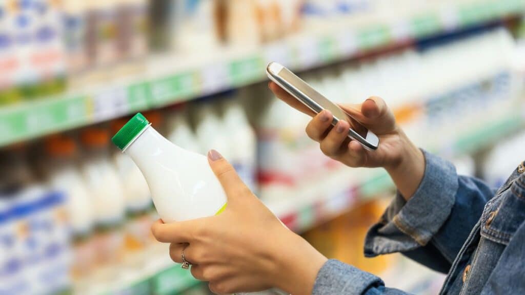 Woman mystery shopping in grocery store taking pictures of milk