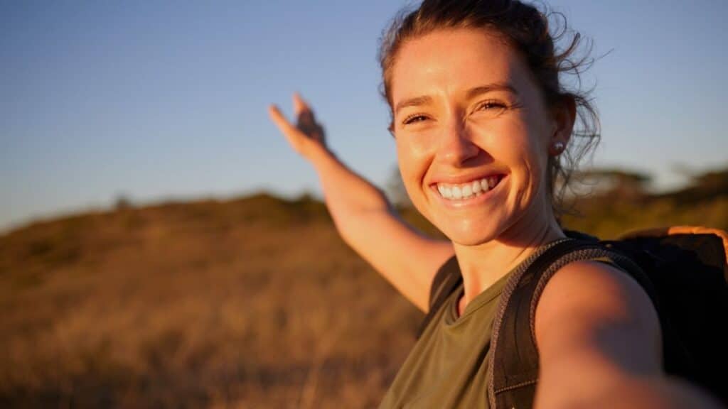 Young woman standing in a field with her arm out