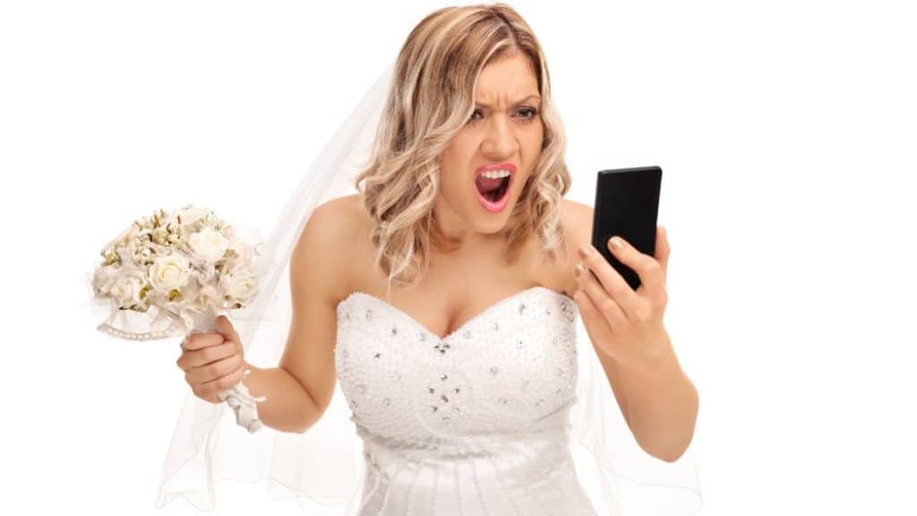 Woman in wedding dress with a bouquet and screaming into a cell phone