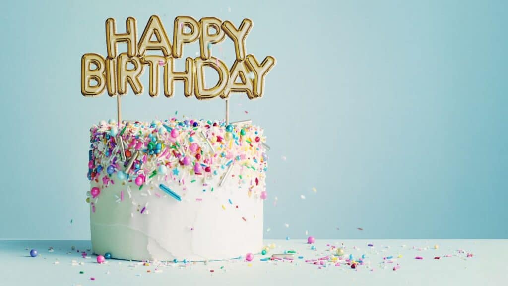 White sprinkle birthday cakes with a topper that says 'happy birthday'