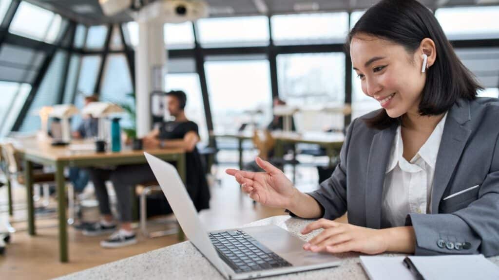 Woman working in office on her laptop wearing air pods