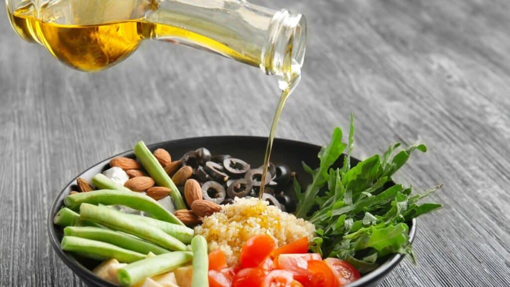 Someone pouring oil on a bowl of food