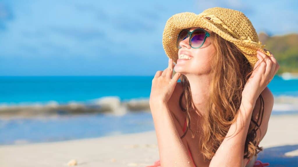 Young woman in a sunhat laying out on the beach