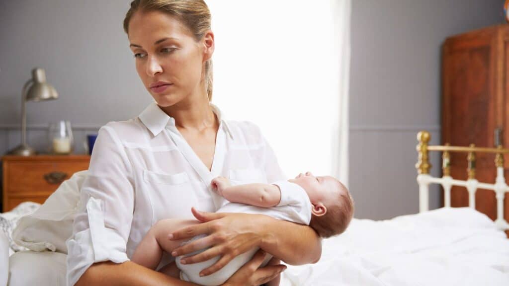 Mother holding her infant and looking upset