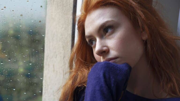 Redhead woman looking upset out the window