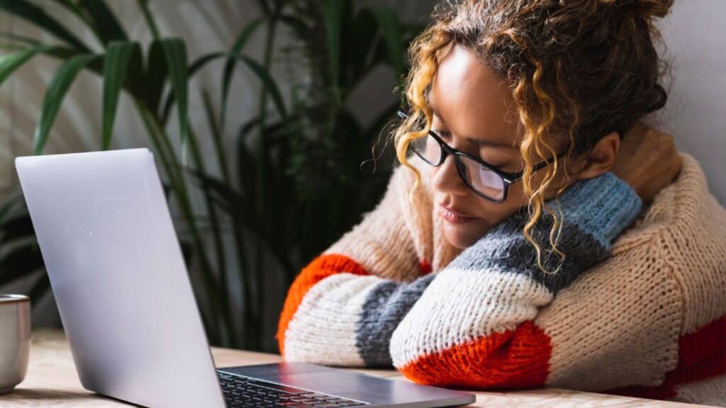 Woman falling asleep while working on her laptop