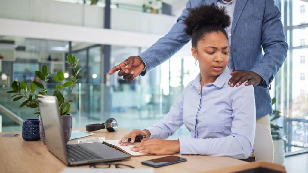 Woman looking annoyed about a man putting his hand on a coworker's shoulder
