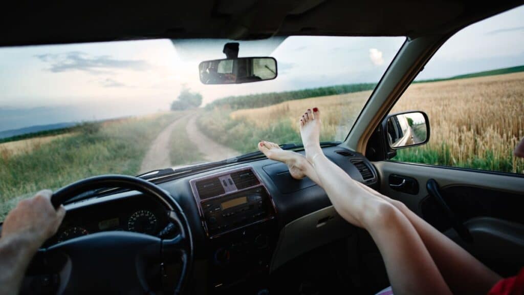 Person sitting in a car with bare feet stretched out on dashboard