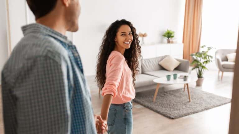 Woman holding man's hand and leading him in to the room
