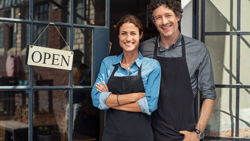 Couple standing at door of business with an "open" sign