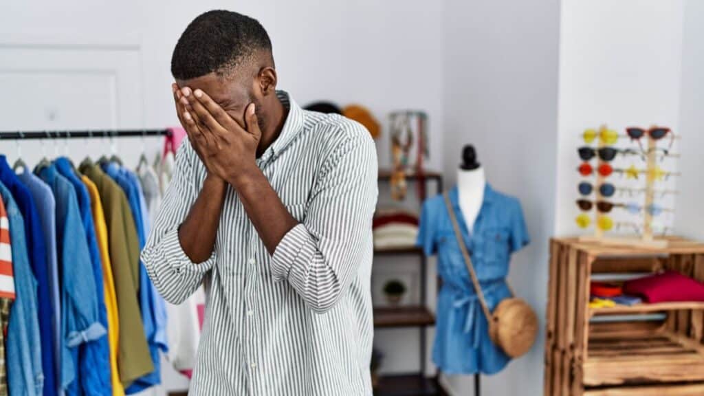 Man looking annoyed and covering his face in a store