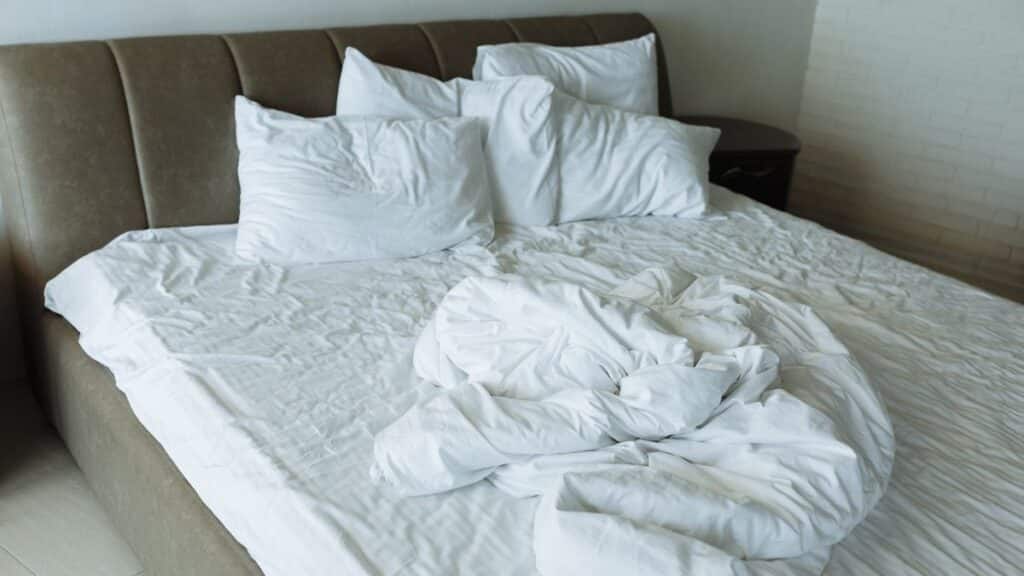 Unmade bed with messy white sheets