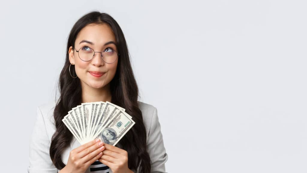 Young woman wearing glasses and holding a handful of cash