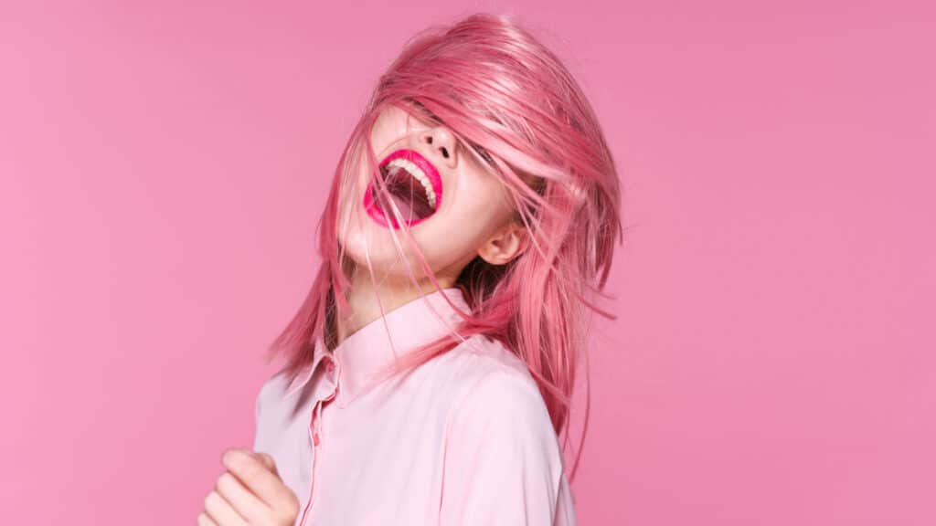 Smiling girl with pink hair and a pink background