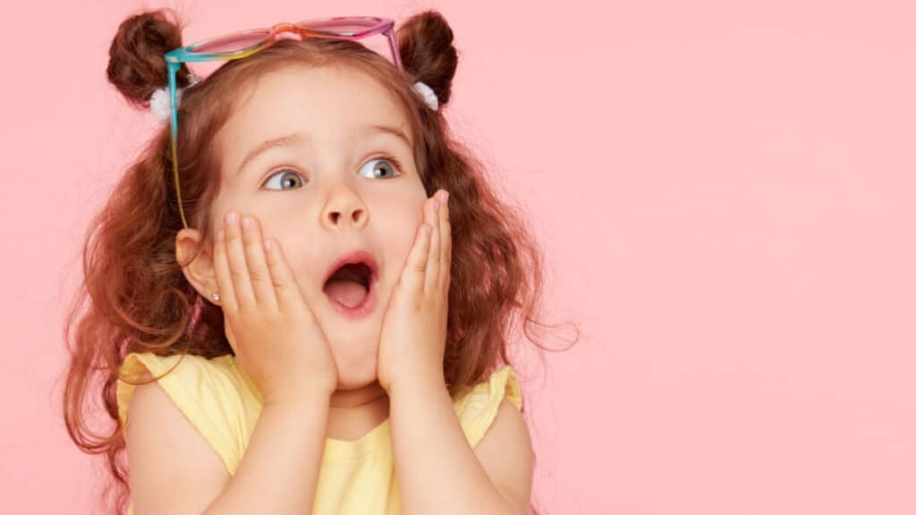 Small little girl with her hands at her face looking surprised