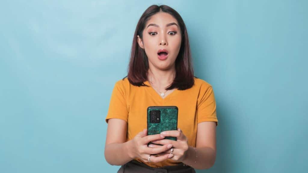 Young woman looking at her phone and looking shocked