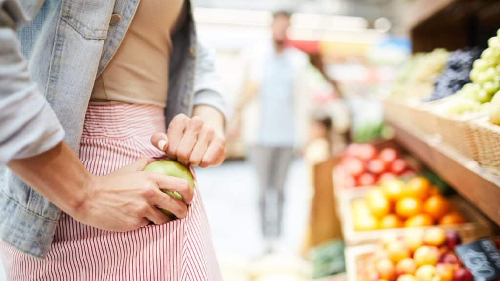 A woman stealing something from the grocery store.