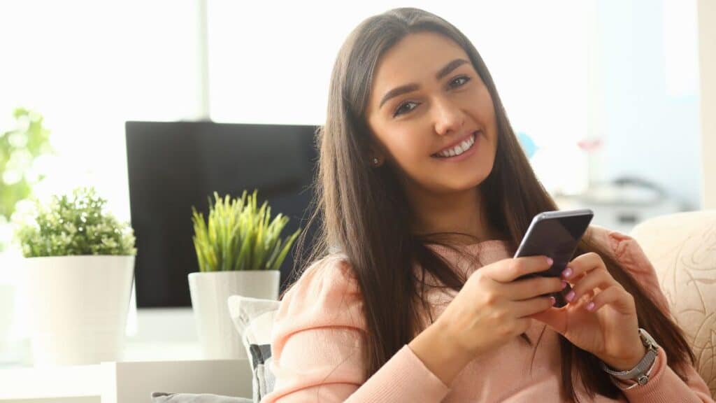 Young girl sitting at her desk and looking at her phone smiling