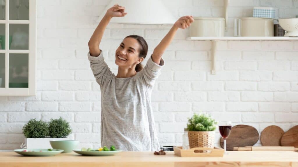 Young woman dancing in the kitchen looking happy