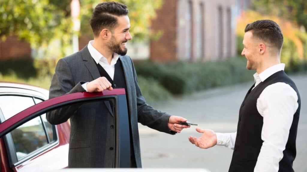 Man handing his car keys to a parking attendant
