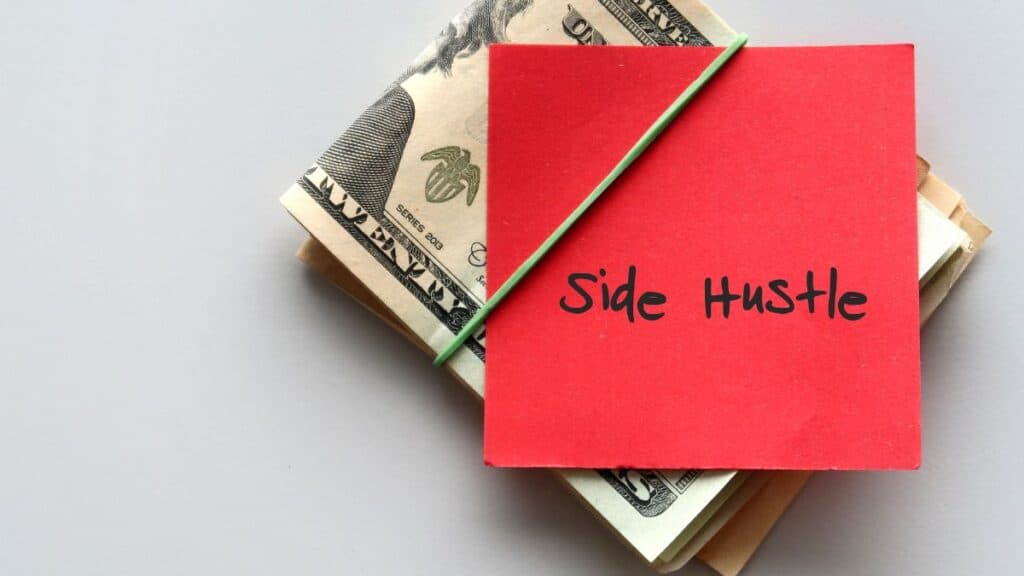 Pile of cash in a rubber band with a red sticky note that says 'side hustle'