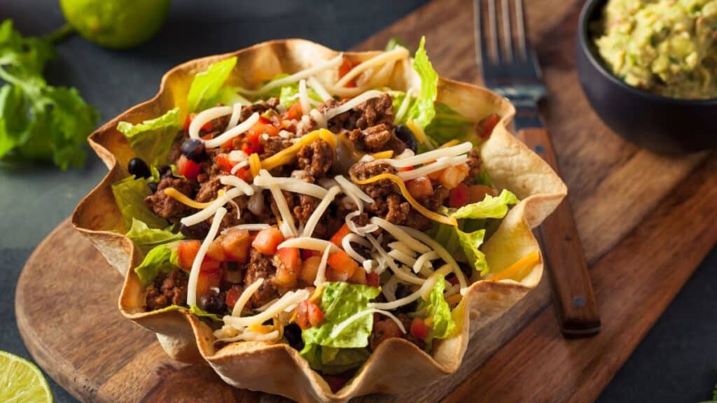 Taco salad in taco bowl on cutting board