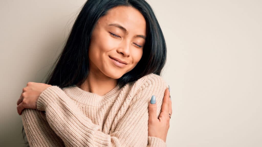 Young woman hugging herself
