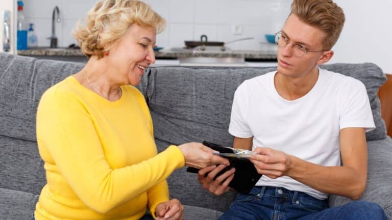 A man handing a woman money while sitting on a couch.