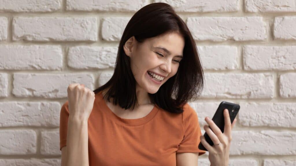 Young woman looking excited as she looks at her phone