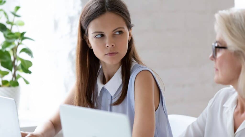 Female coworkers looking frustrated with each other while working