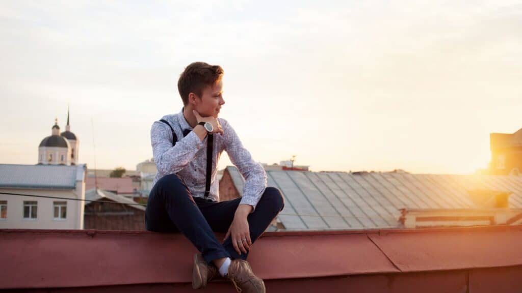 A woman sitting on a rooftop wearing a mans outfit.