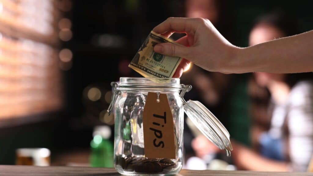 Hand putting money in a tip jar