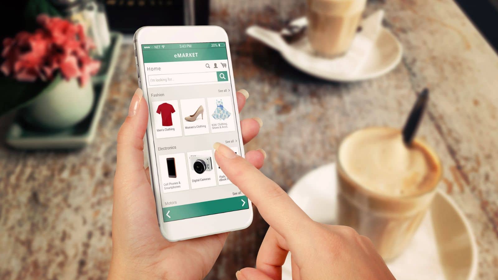 Person sitting at table with coffee cups shopping for clothes on an app