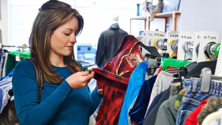 Woman looking through racks of clothing at thrift store