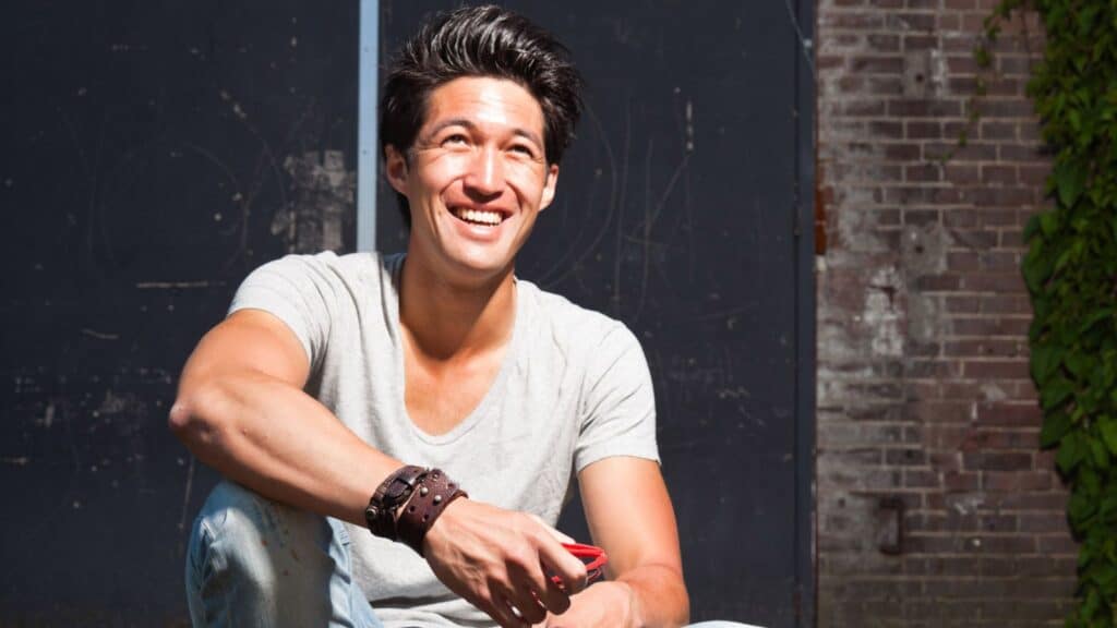 Asian man sitting on steps smiling
