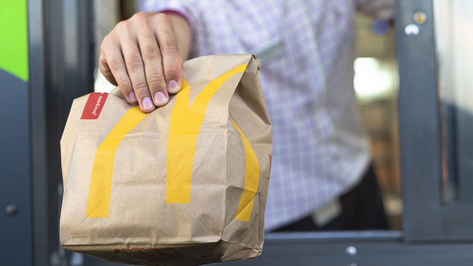 Person handing a bag of food in a McDonald's drive-thru