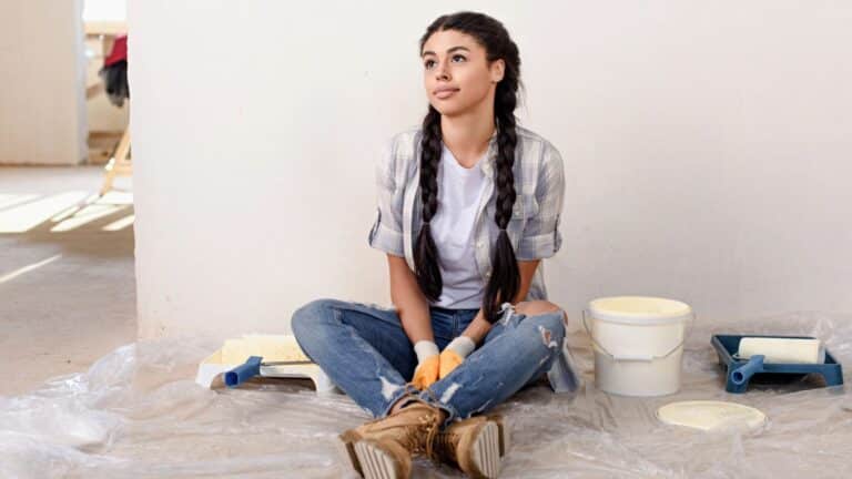 Young woman sitting against a wall while working on home