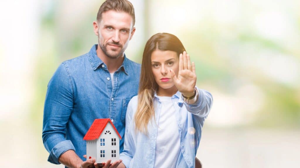 Couple looking angry holding a small house model