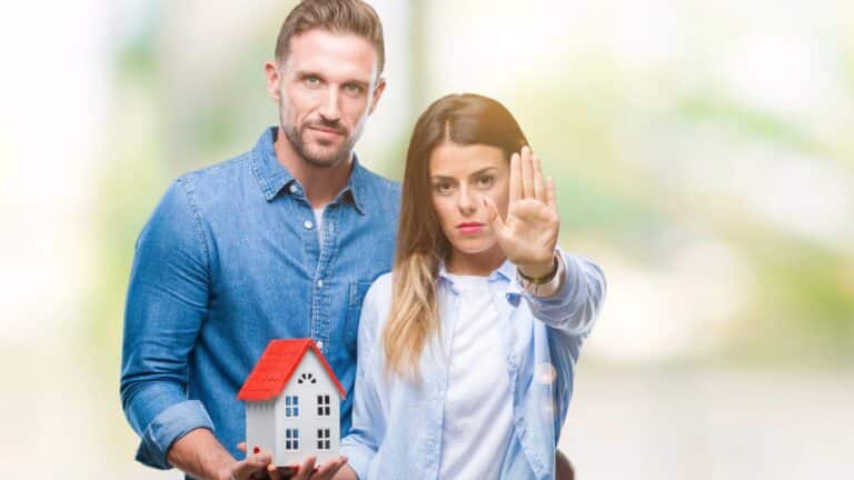 Couple looking angry holding a small house model
