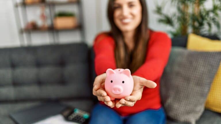 Young woman holding out a piggy bank