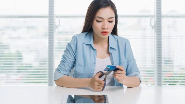 Woman sitting in front of a window cutting up a credit card