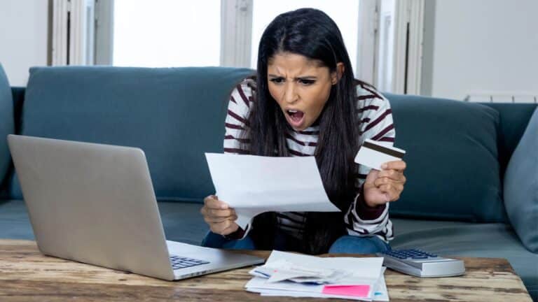 Young woman looking shocked when paying bills