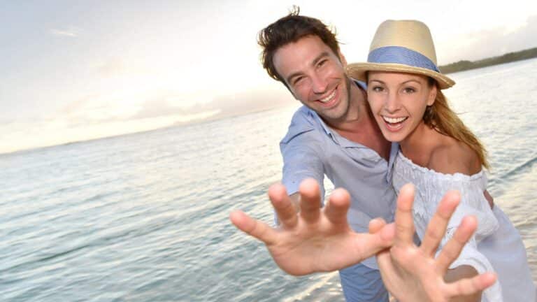 Young couple holding their hands out on the beach