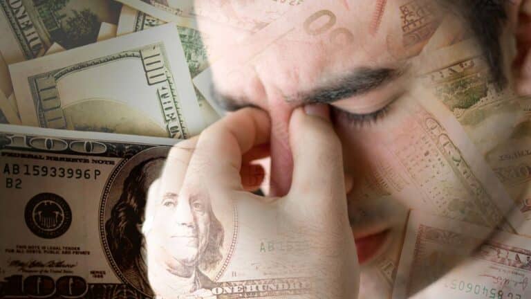 Man looking stressed about money with cash in the background